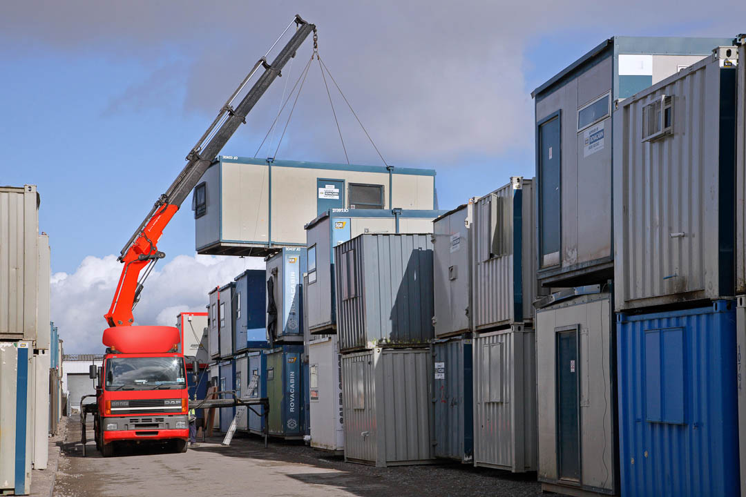 DAF crane truck lifting three high stacked cabins