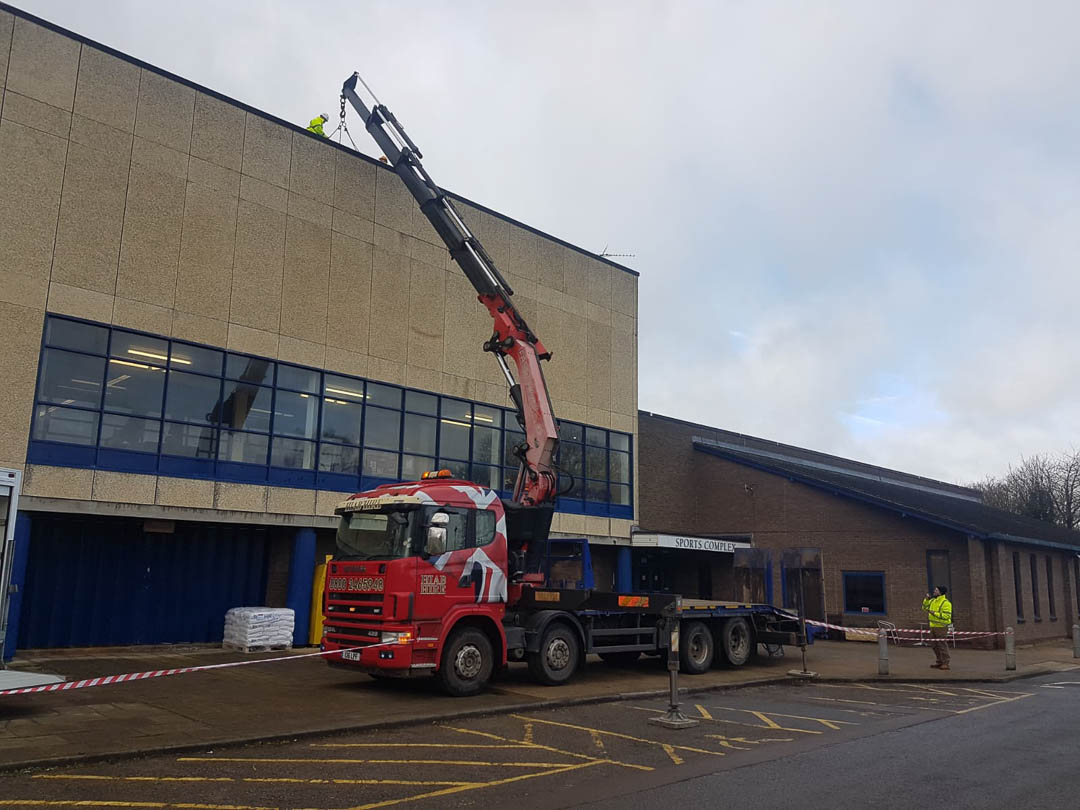 Fassi Crane lifting materials to to second floor roof